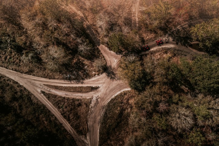 Aerial view of a Y-shaped dirt road intersection surrounded by trees.